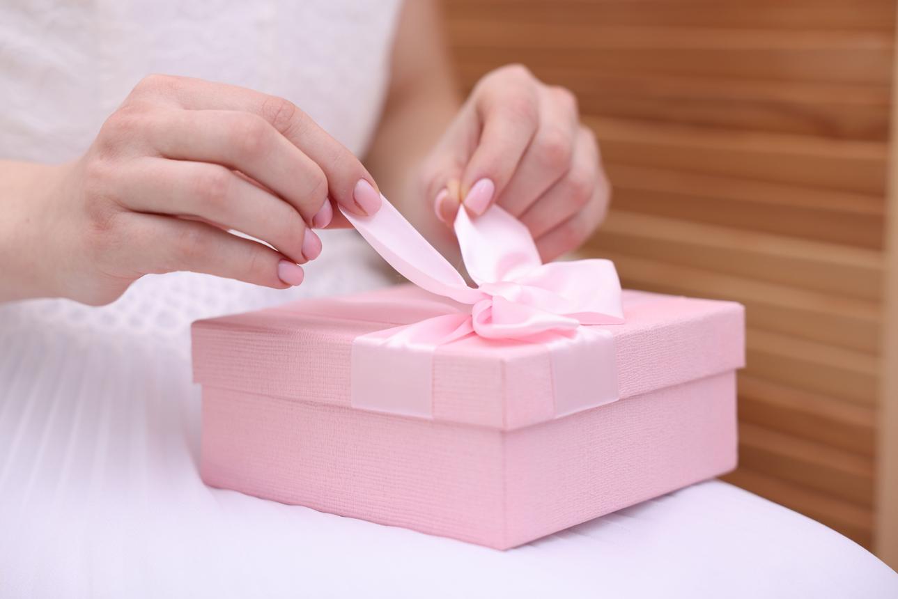Bride opening beautiful wedding gift indoors, closeup