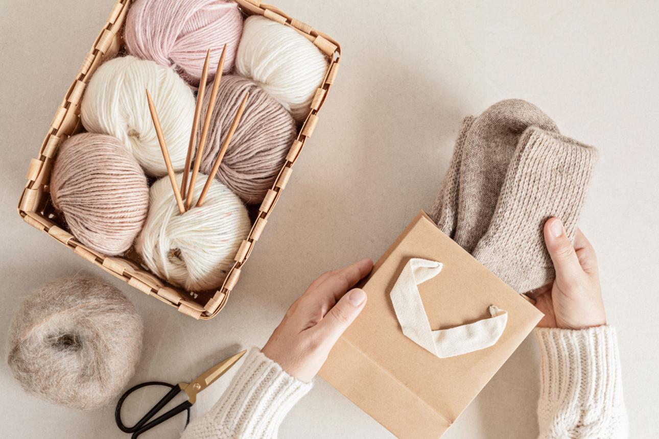 Craft hobby background with yarn in natural colors and handmade socks. Recomforting hobby to reduce stress for cold fall and winter weather. Mock up, top view