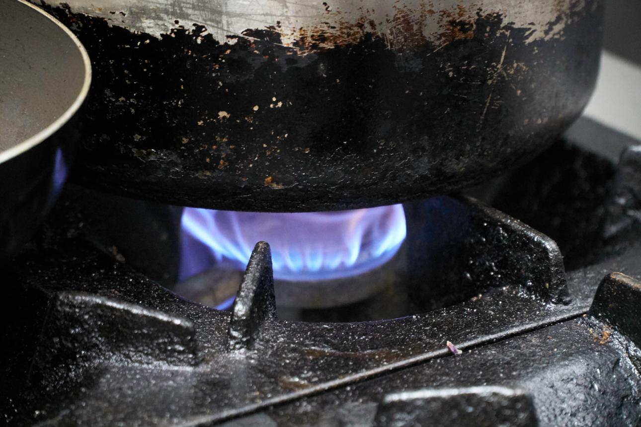 Gas burning under and old and dirty stainless saucepan