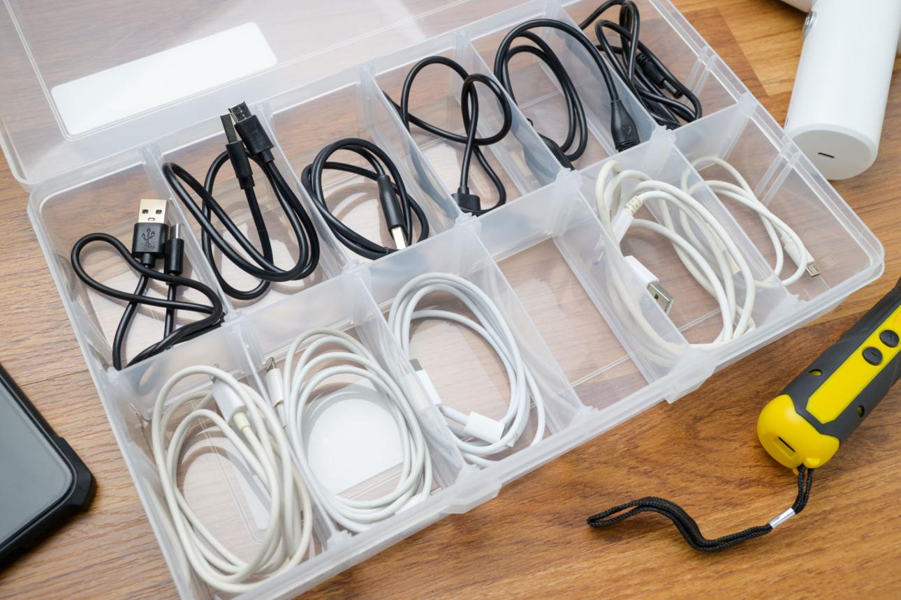 Many USB charging cables stored in a plastic storage box