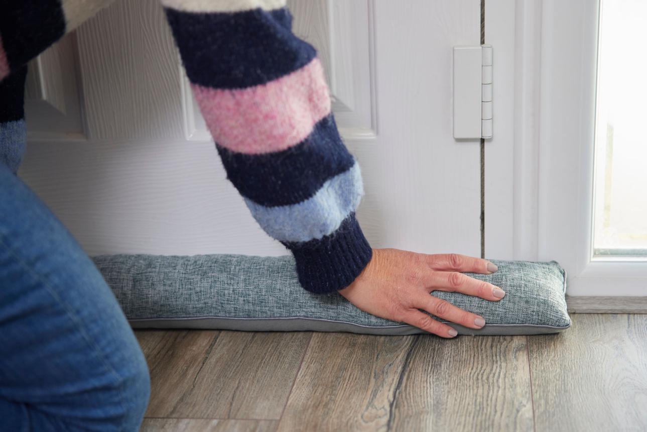 Woman Saving Enegy Insulating Home Putting Draught Excluder Tape On Window